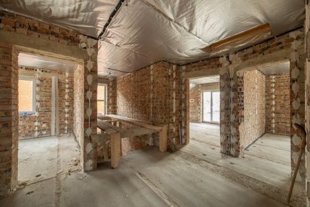 Interior of unfinished brick house with concrete floor and bare walls ready for plastering under construction. Real estate development